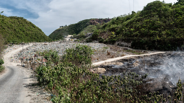 Eine offene Mülldeponie in Consolacion, Philippinen, im Vordergrund steigt Rauch aus den Abfällen.