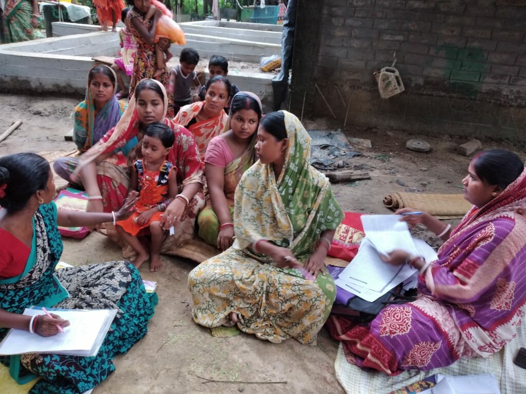 Mehrere indische Frauen in traditioneller Kleidung sitzen in einem Schulungszentrum von Pater Lawrence auf dem Boden und haben Unterricht.